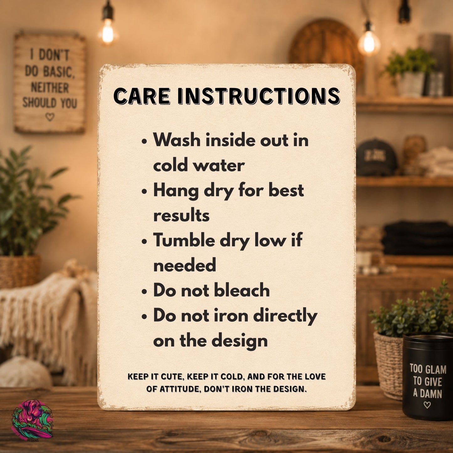 A decorative rectangular sign with a distressed cream background and black text reading 'CARE INSTRUCTIONS' with bullet points for washing, hanging, drying, bleaching, and ironing. The sign is photographed in a warm, rustic room setting on a wooden table, with shelves, plants, and hanging bulbs in the background.