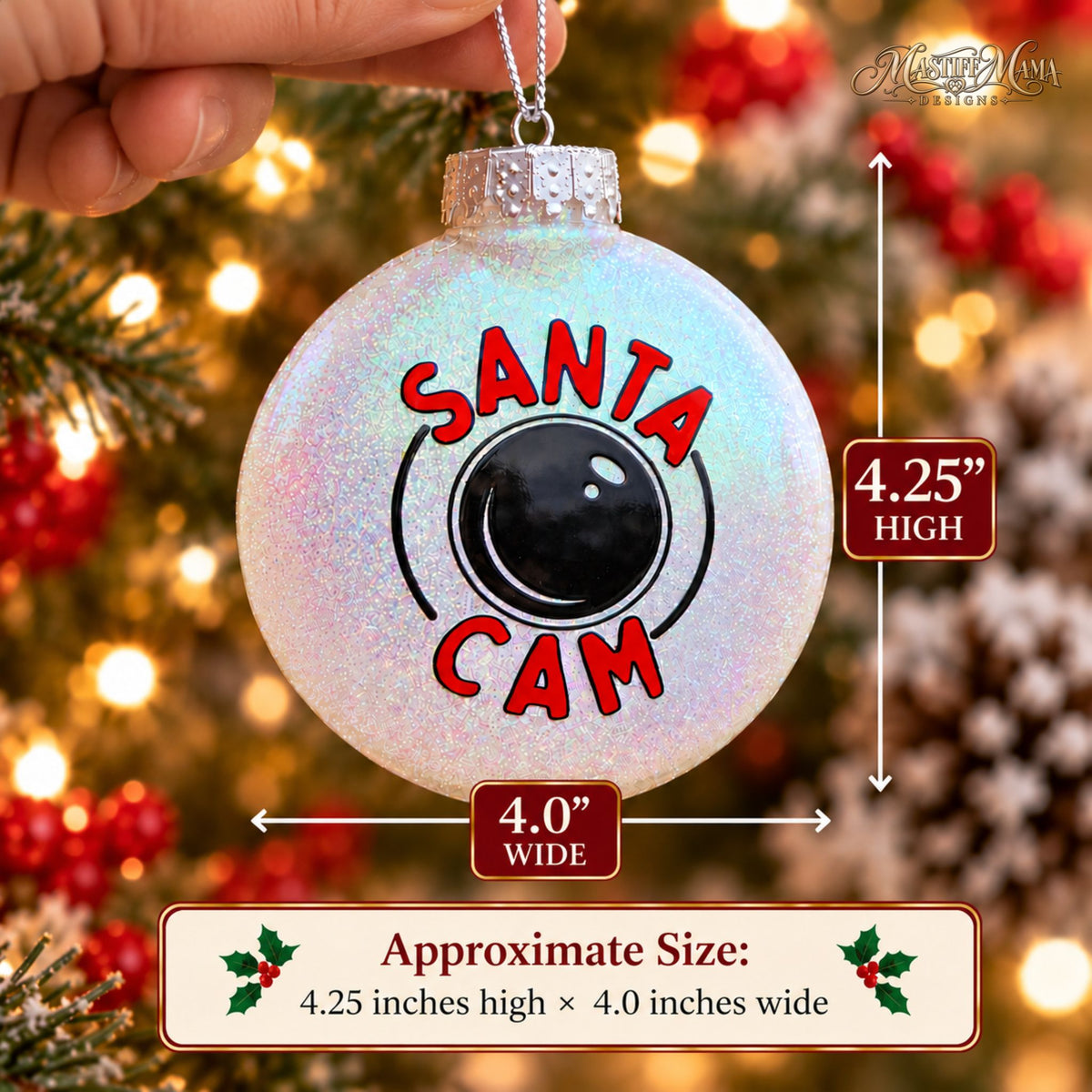 Handmade glitter Santa Cam plastic Christmas ornament with red lettering and a black camera design being held up in front of a holiday tree. Approximate sizing info provided.